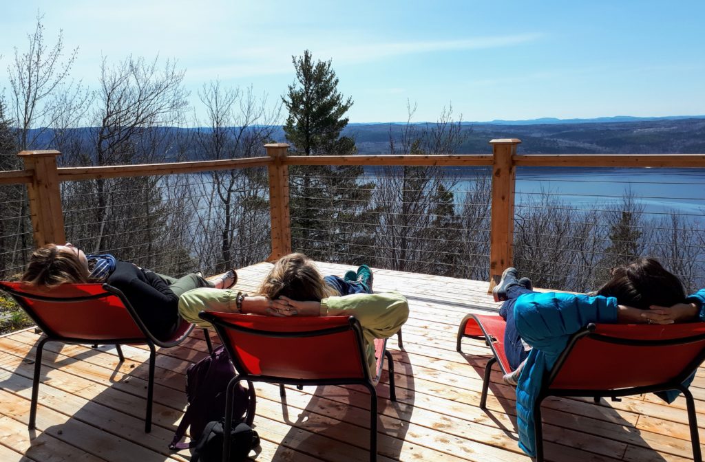 Your Guide to Where to stay in Quebec: Unique Farms to Futuristic Pods in the woods 3 Cap du Leste Quebec @DownshiftingPRO sitting on the deck facing the Saguenay Fjords