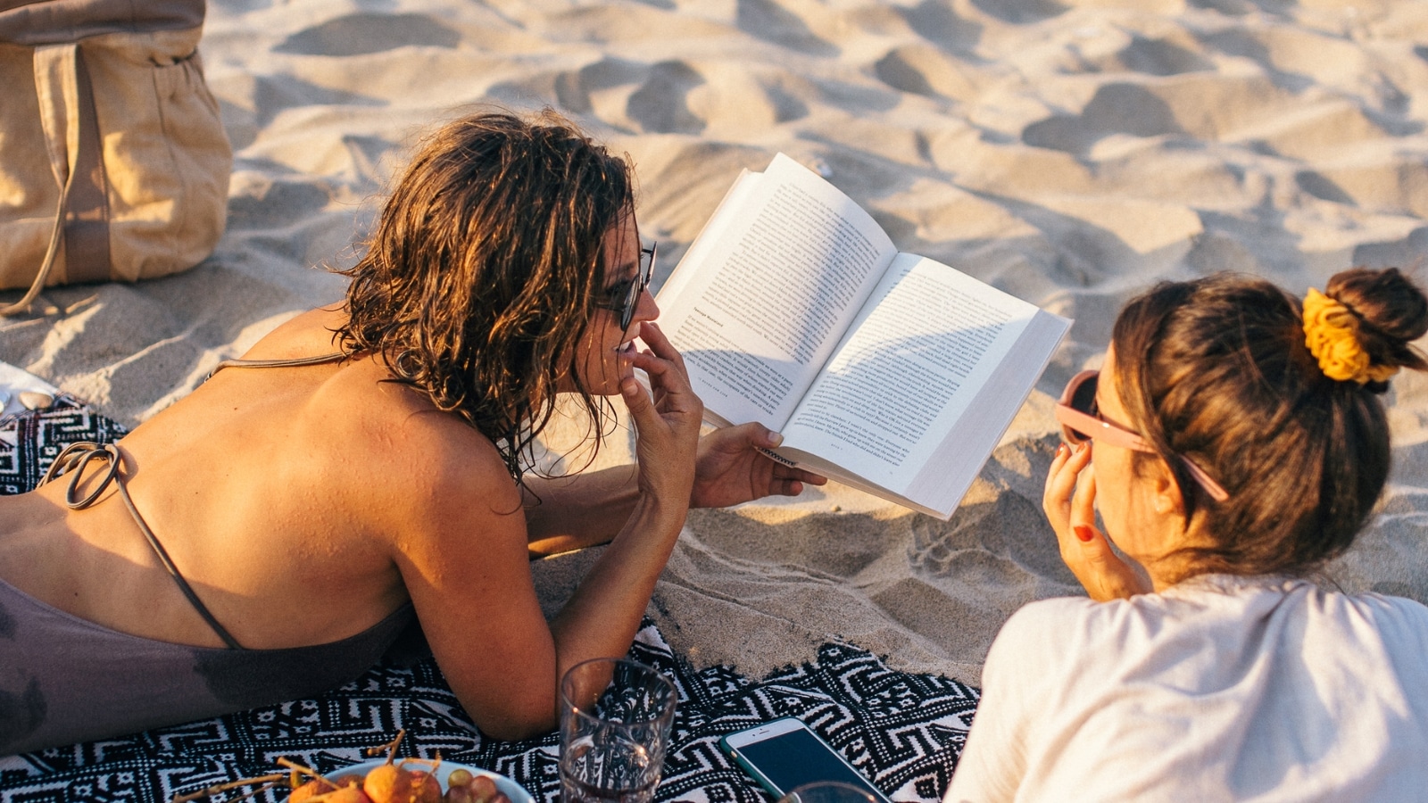 Women reading on the beach Photo Credit Anna Tarazevich CanvaPro